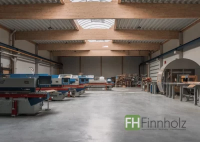 Innenansicht der Produktionshalle mit Büro in Lage mit Brettschichtholzbindern und Lichtband.