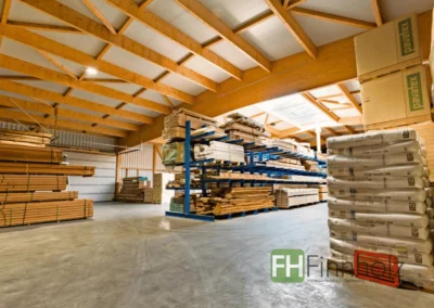 Innenansicht der freitragenden Lagerhalle mit sichtbarer Holzkonstruktion und Regalen für Holzprodukte.